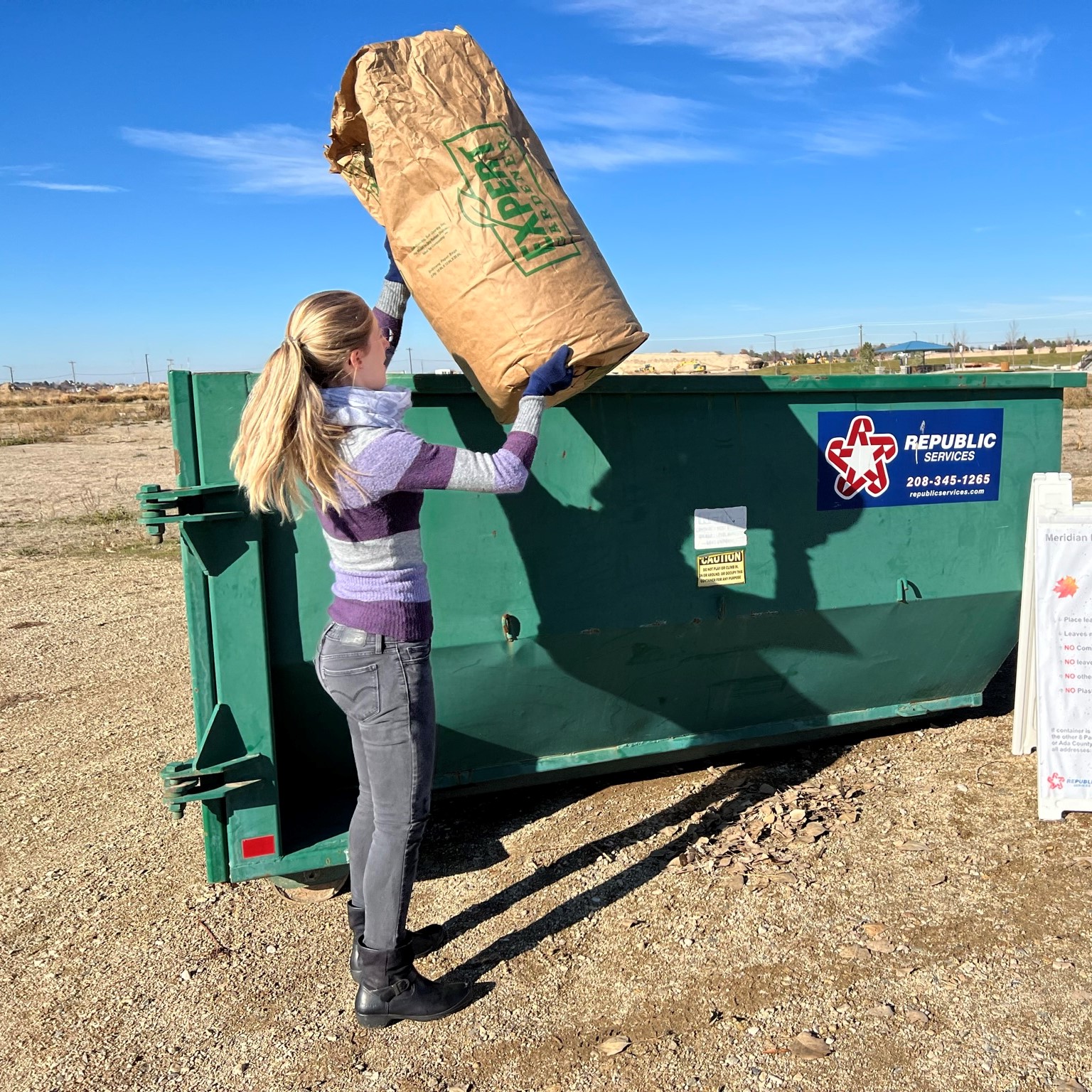 Peron putting large brown paper leaf bag in a leaf bin at Discovery Park in Meridian